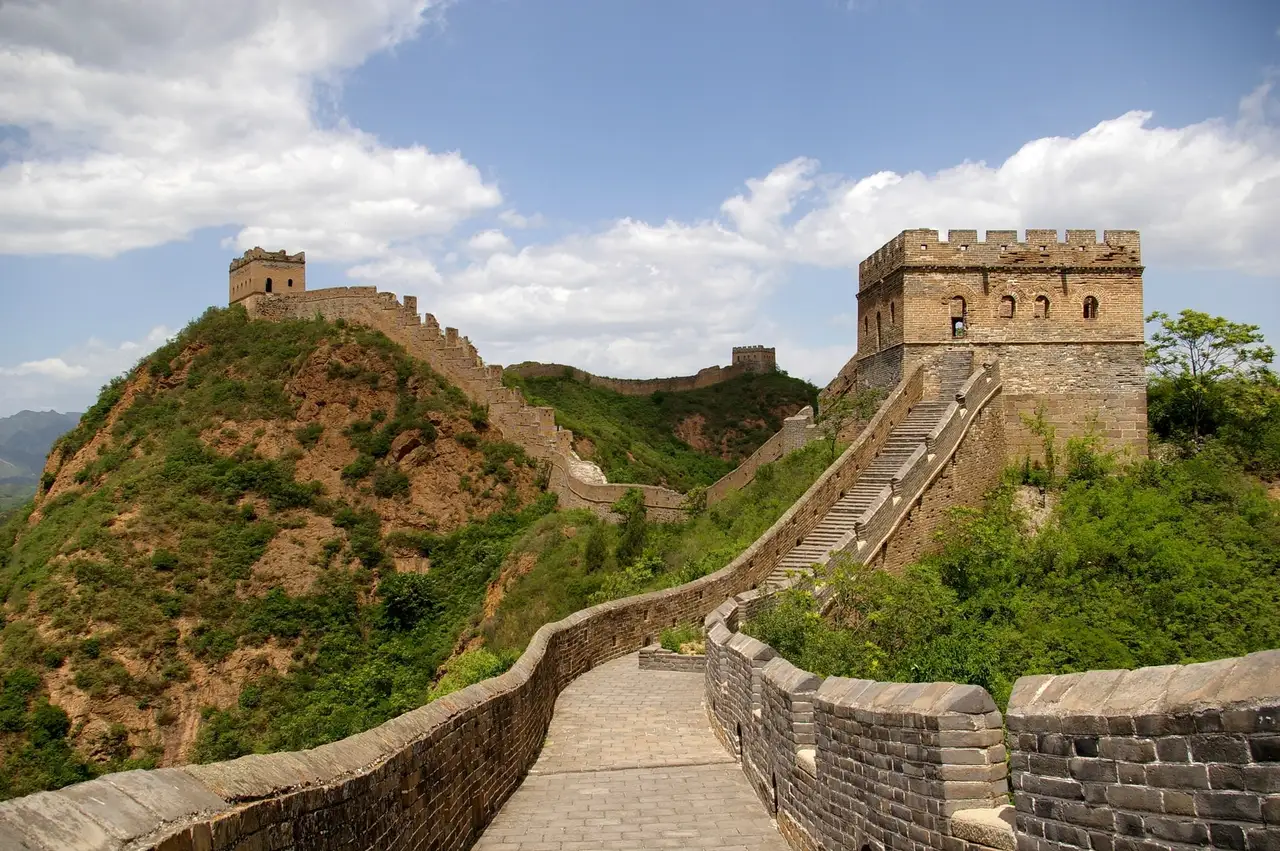 The Great Wall of China at Jinshanling, its paved walkway climbing green hills to a brick watchtower