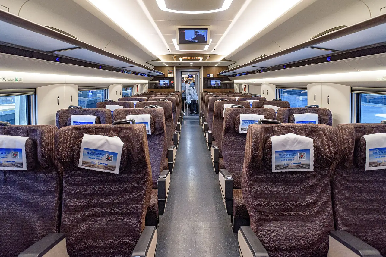 First class carriage of a CR400AF train with wide burgundy seats arranged two and two either side of the aisle