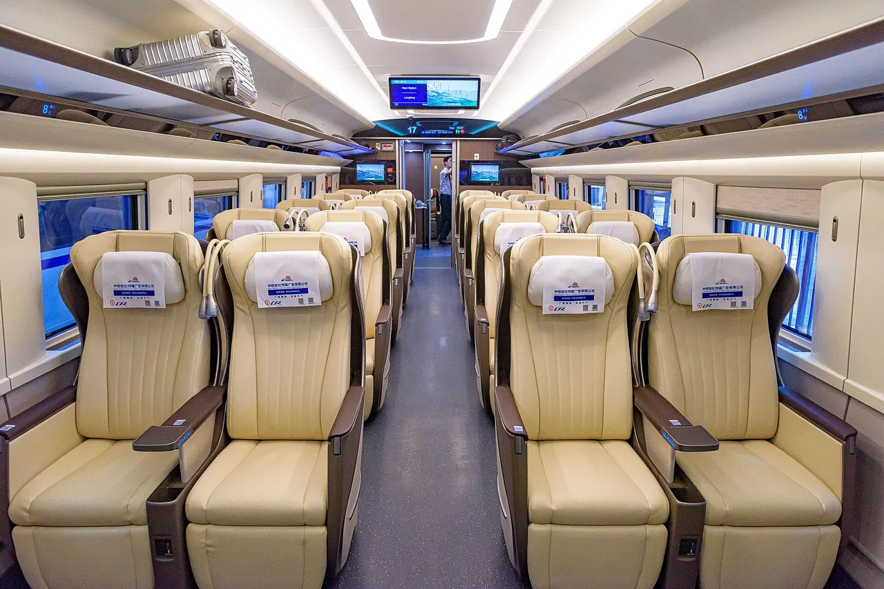 Premium first class carriage with cream leather shell seats arranged two and two, each with a white headrest cover