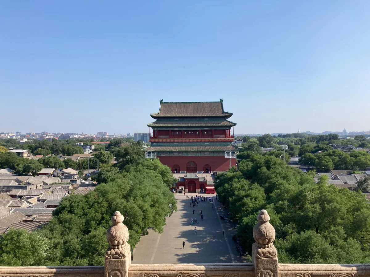 The Drum Tower of Beijing seen from the Bell Tower, with a tree-lined square and grey hutong roofs on either side