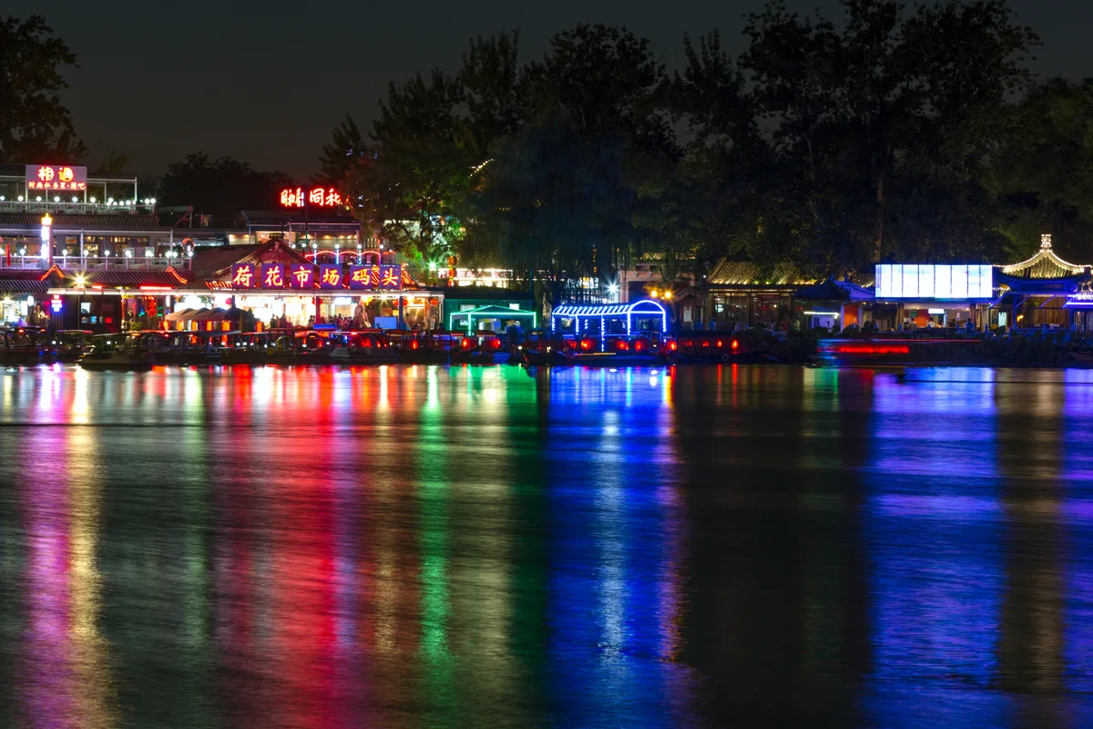 Neon lights of lakeside bars and restaurants reflected in the water of Houhai at night