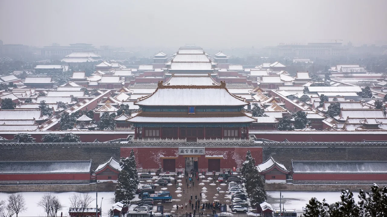 Snow on the roofs of the Forbidden City seen from Jingshan Park, with the Meridian Gate in the middle of the frame and the city grey in haze beyond