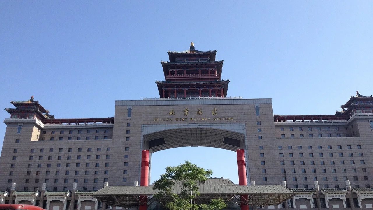 The gate building of Beijing West railway station, with a three-tiered red and green pavilion on top of a huge arch, under a clear blue sky