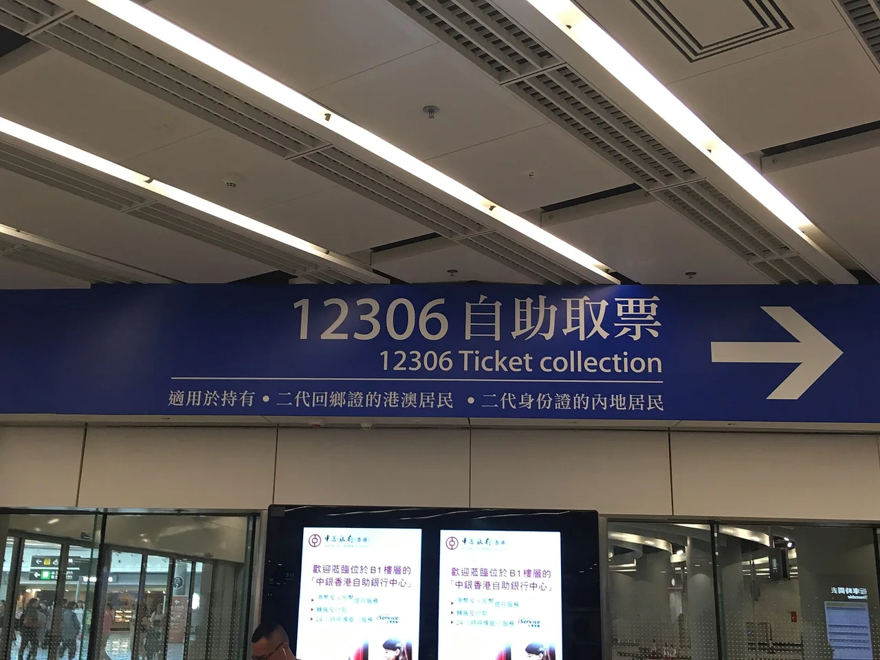 A sign for 12306 ticket collection machines above a row of machines at Hong Kong West Kowloon station