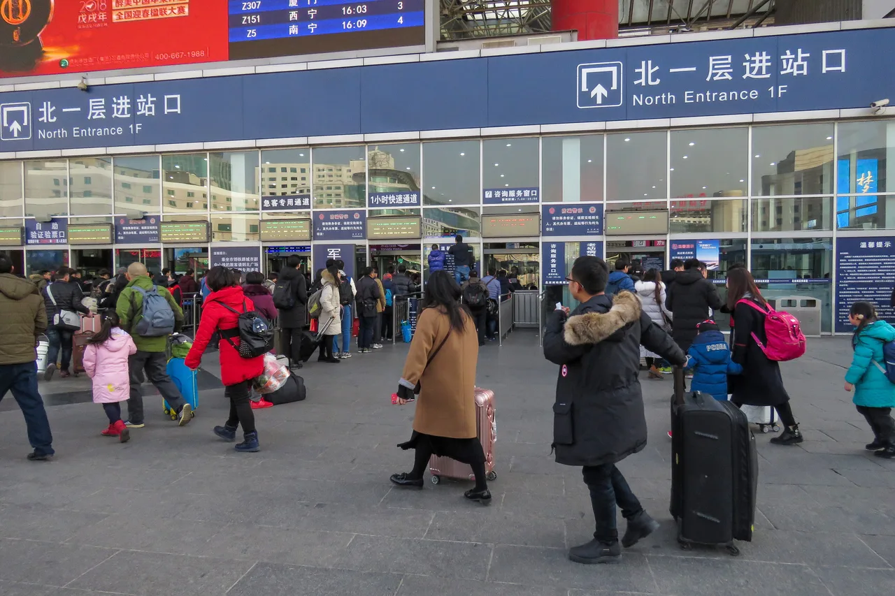 Travellers with luggage streaming through the north entrance of Beijing West Railway Station in winter clothes