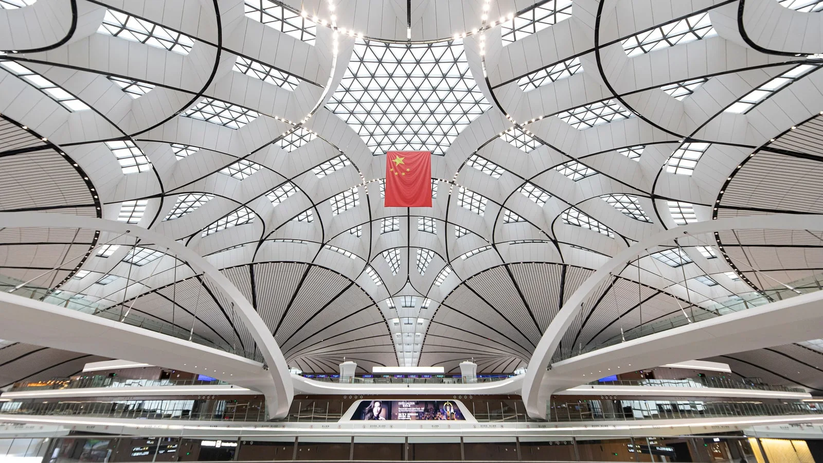 The white star-shaped roof of Beijing Daxing International Airport with a Chinese flag hanging under the central skylight