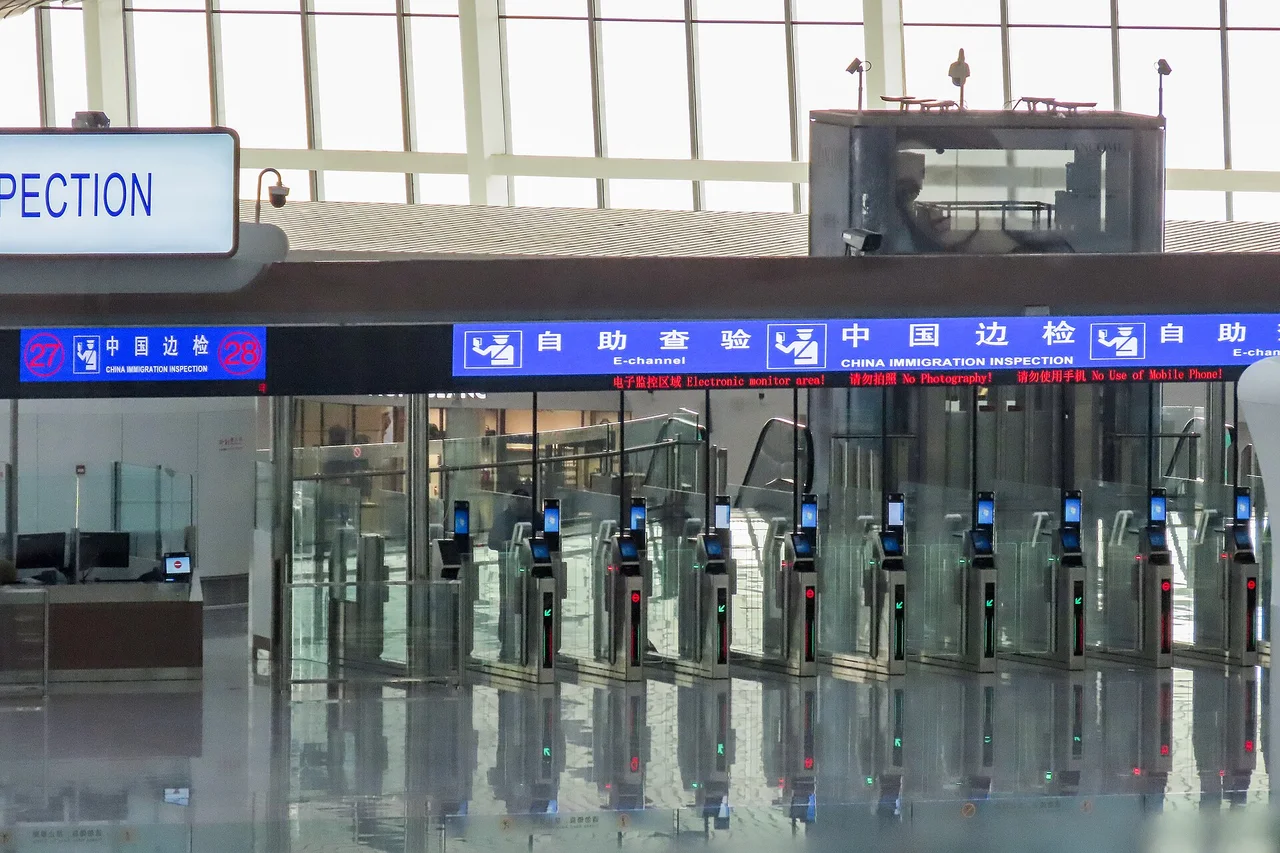 A row of glass self-service gates under blue China Immigration Inspection signs at Beijing Daxing airport