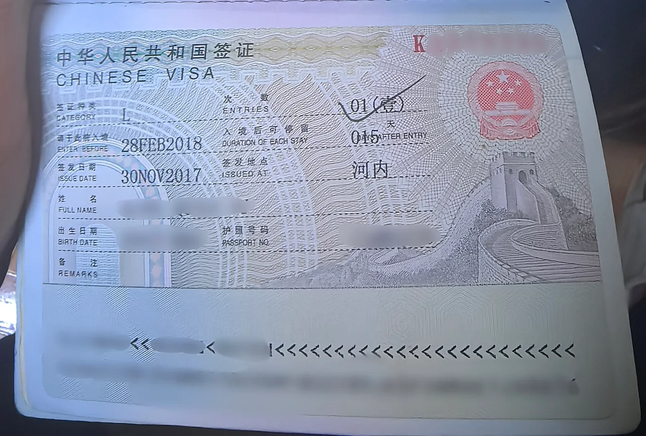 A Chinese L visa sticker in a passport, category L, single entry, 15 days per stay, with the holder's name and passport number blurred