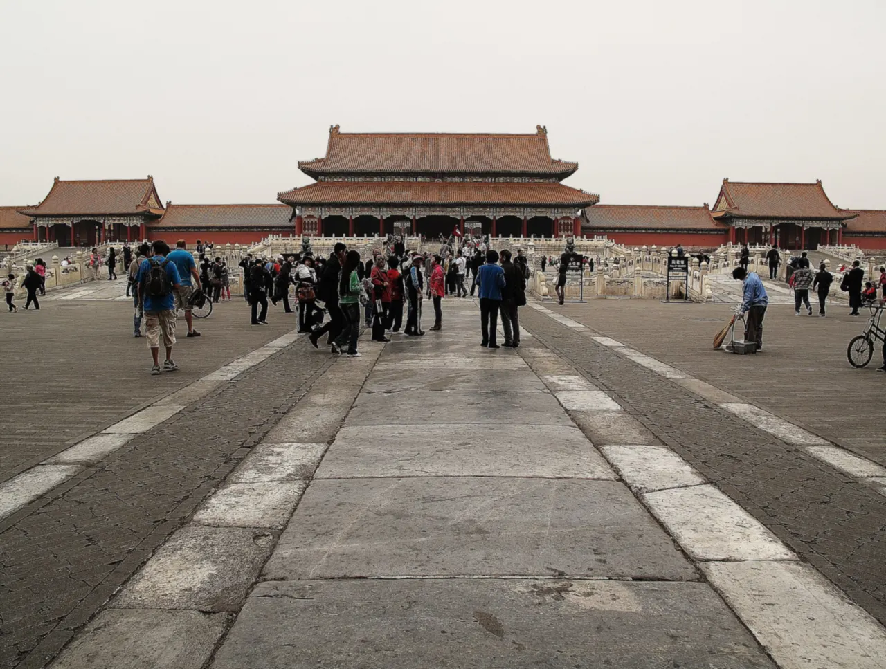 The Gate of Supreme Harmony with its double roof at the end of a wide stone courtyard, visitors walking along the central path