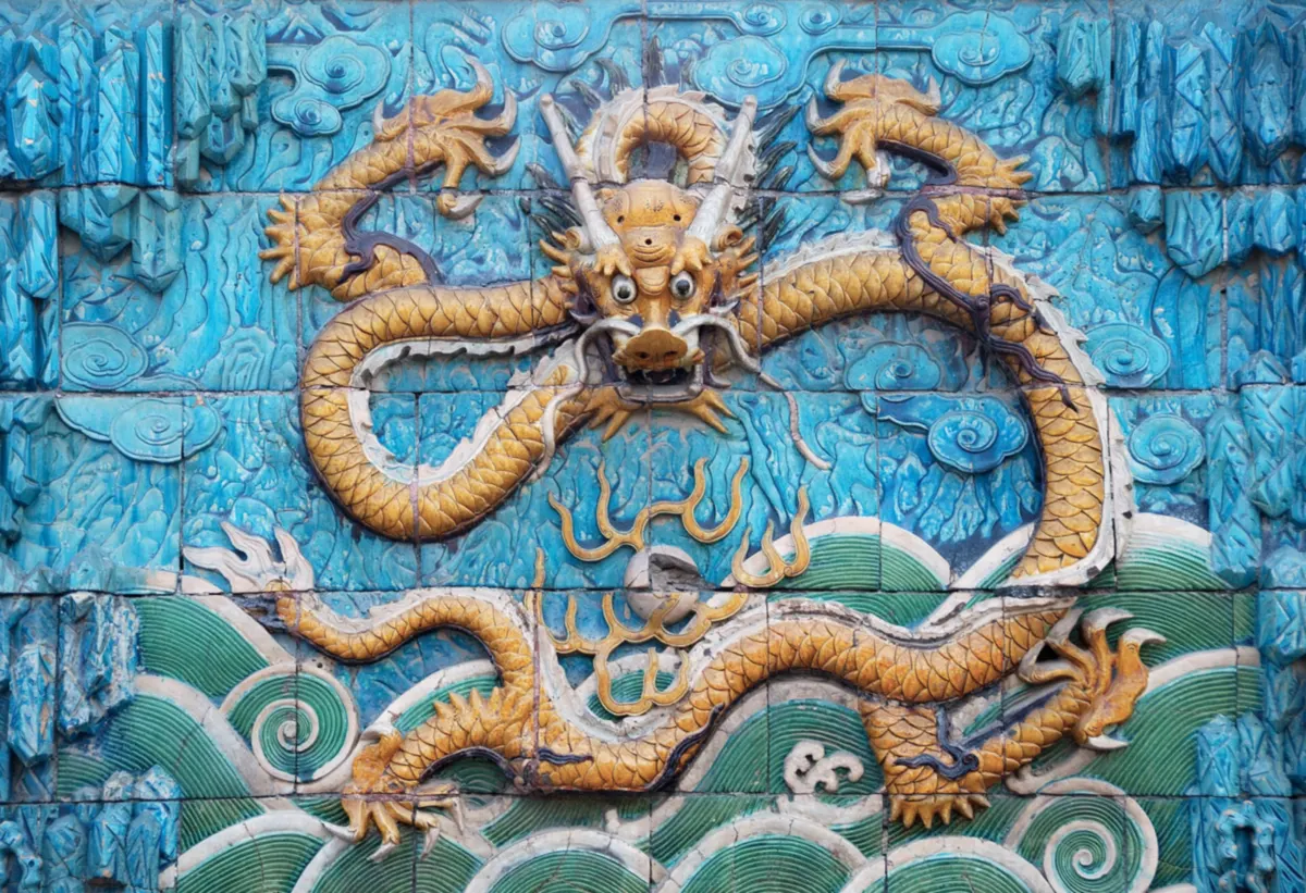 A yellow glazed dragon coiled against a blue and green tiled background on the Nine-Dragon Screen