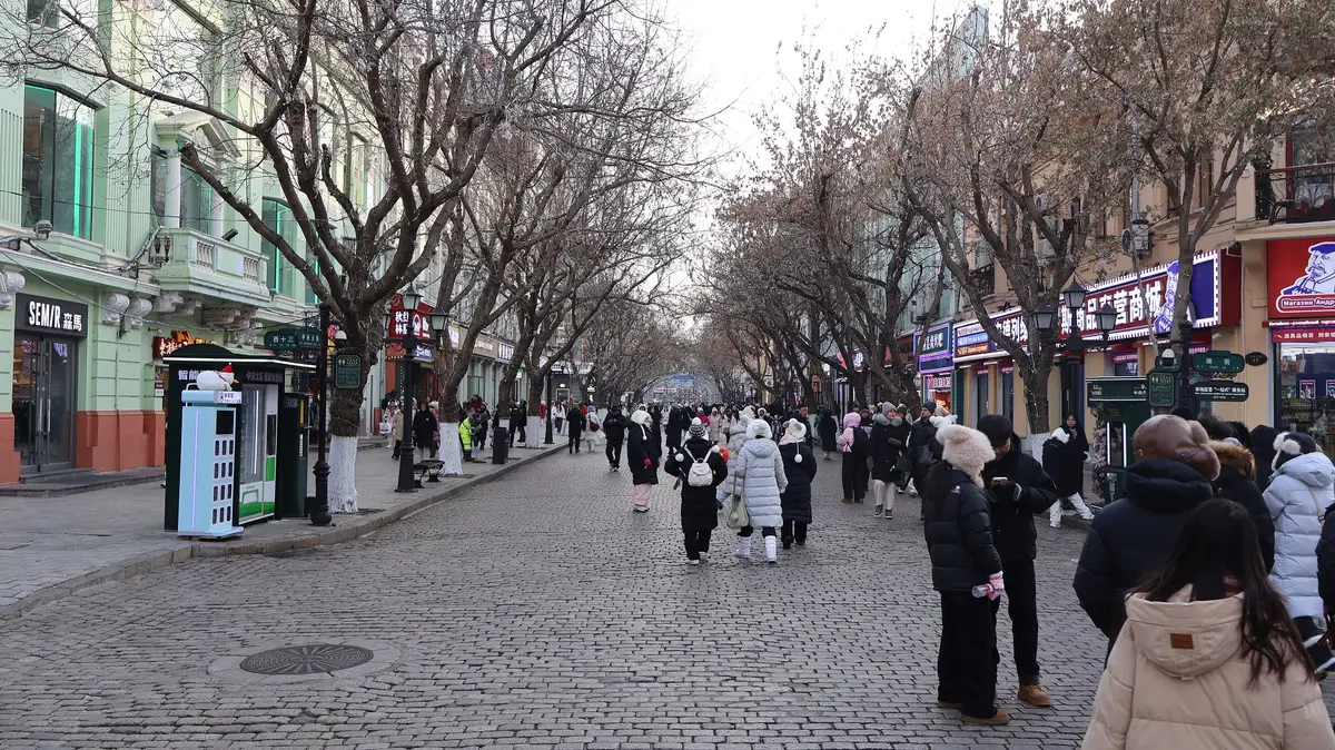 Central Street in winter, with bare trees over the cobbled pedestrian street and people in long padded coats and hats walking between the old shopfronts