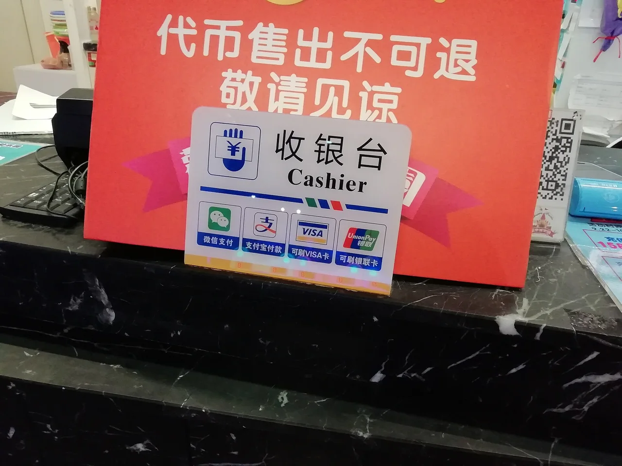 A cashier sign on a shop counter in Suzhou showing the WeChat Pay, Alipay, Visa and UnionPay logos