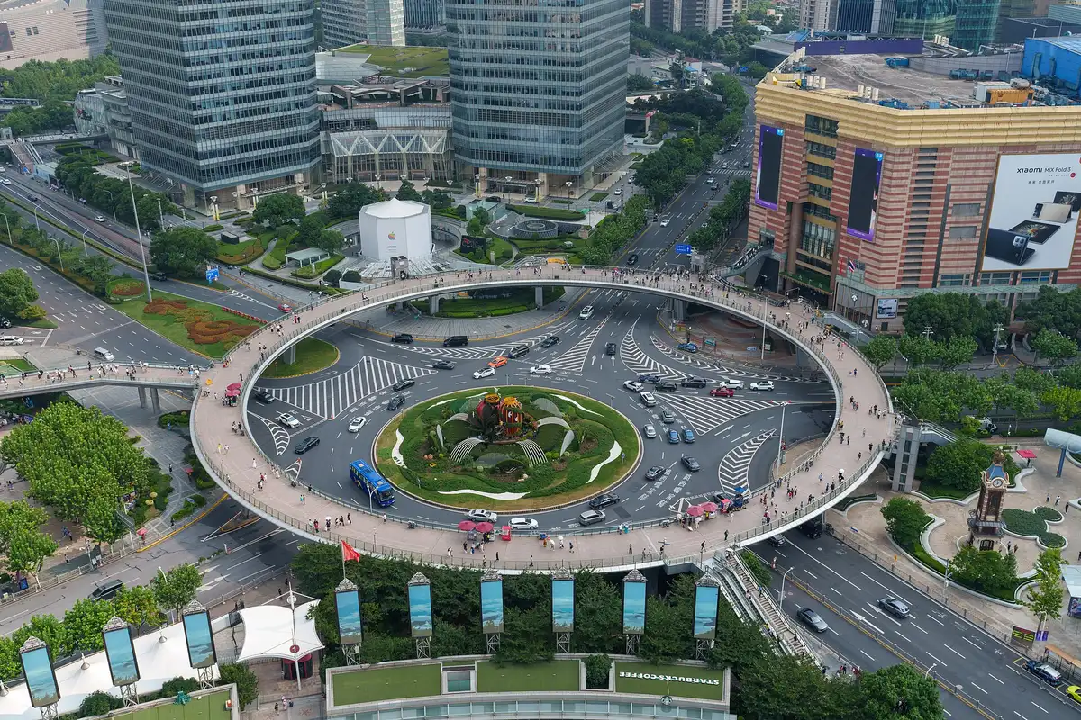 A ring-shaped elevated footbridge over a busy roundabout among office towers and a shopping centre in Lujiazui
