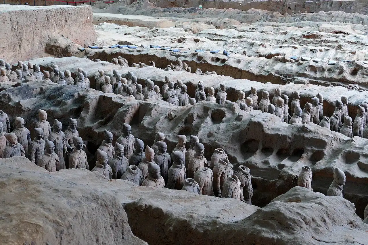Dozens of terracotta warriors standing in rows between ridges of excavated earth in Pit 1