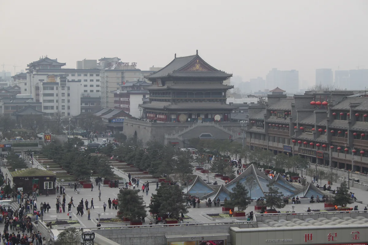 The Drum Tower at the far end of a paved square with trees and glass pyramids, seen from above on a hazy day
